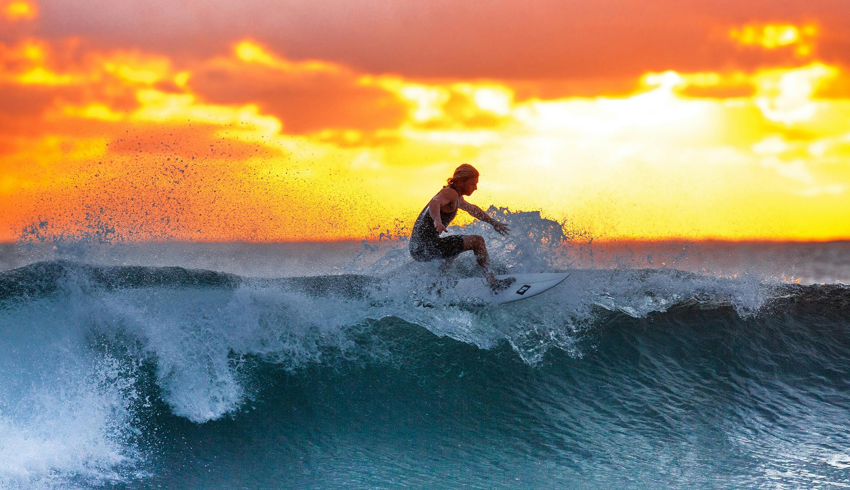 Surfer riding a wave at sunset